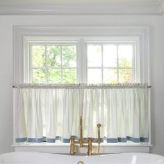 a bath tub sitting under a window next to a white sink and counter top with a faucet