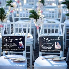 two chairs with signs on them sitting in front of some white chairs and decorated with flowers