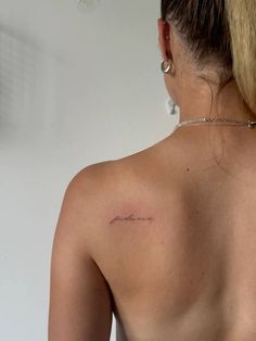 the back of a woman's shoulder with a small tattoo on her left side