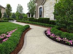 a driveway with flowers and bushes around it