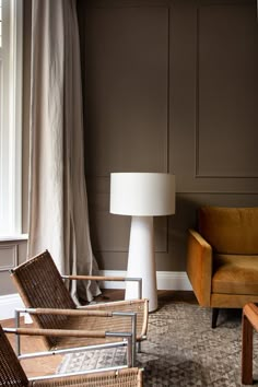 a living room filled with furniture and a lamp next to a window on top of a rug