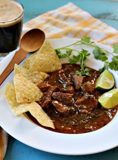 a white plate topped with meat and tortilla chips next to a cup of coffee