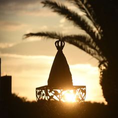 the sun is setting behind a decorative light fixture