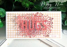 a close up of a greeting card with the word hug on it and flowers in the background