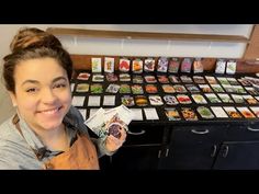 a woman standing in front of a table full of sushi and other food items