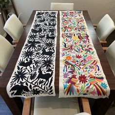 the table runner is decorated with colorful flowers and birds on black, white, and multicolored fabric