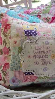 a white basket filled with pillows covered in colorful fabric and words on it's sides