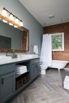 a bathroom with gray cabinets and white towels on the counter, along with a tub