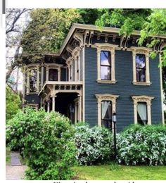 a blue house with trees and bushes around it