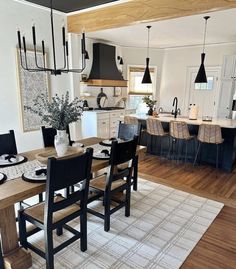 a dining room and kitchen area in a house with hardwood floors, white walls and black accents