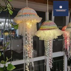 three jellyfish lights hanging from the ceiling in front of a window with greenery