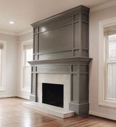 an empty living room with a fireplace and two windows