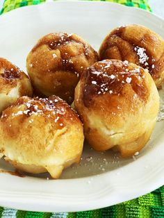 small pastries are on a white plate with sugar sprinkled on top, sitting on a green tablecloth