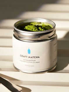 a jar of green food sitting on top of a table next to a knife and fork