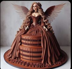 there is a cake that looks like a woman sitting on top of a barrel with wings