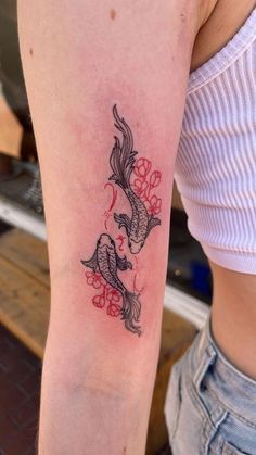 a woman with a tattoo on her arm that has two koi fish in it