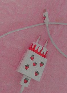 a white bag with strawberries on it is hooked up to a charger and cord