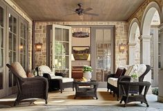 a living room with wicker furniture and large windows on the outside wall, along with wood flooring