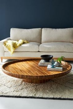 a living room with a white couch and wooden coffee table in the middle, against a dark blue wall