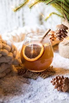 a glass jar filled with liquid sitting on top of a table next to pine cones