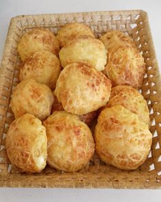 a wicker basket filled with cheesy pastries on top of a table