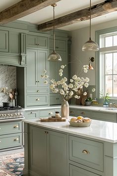 a kitchen with green cabinets and white flowers in a vase on the island countertop