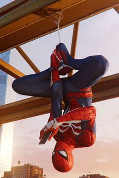 a spider - man hanging upside down from the ceiling in front of a cityscape