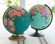 two decorative globes sitting on top of a table next to each other in front of a window