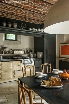 a table with food on it in a kitchen next to a brick wall and ceiling