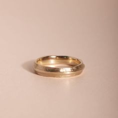 a close up of a gold wedding ring on a white surface