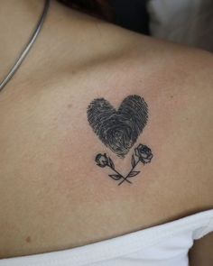 a woman with a tattoo on her shoulder has a heart shaped fingerprint and three roses