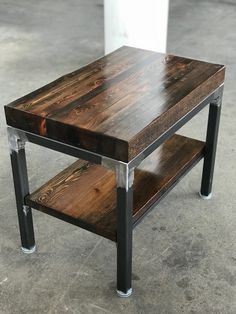 a wooden table sitting on top of a cement floor next to a metal pipe holder