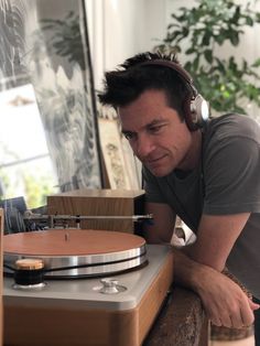 a man wearing headphones leaning over a record player