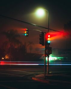 the traffic lights are red, green and blue at an intersection on a foggy night