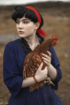 a woman holding a chicken in her hands