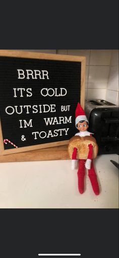 an elf is sitting next to a sign that says, brrr its cold outside but i'm warm & toasty