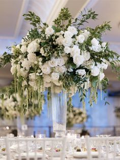 a vase filled with white flowers sitting on top of a table covered in place settings