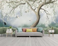 a living room with a couch, table and wall mural on the wall that has a tree in front of it