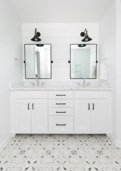 a bathroom with two sinks, mirrors and lights on the wall above them is decorated in black and white