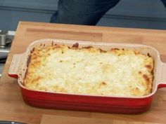 a red casserole dish sitting on top of a wooden cutting board