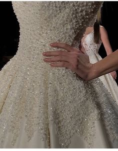 a woman in a wedding dress with her hand on the back of it's skirt