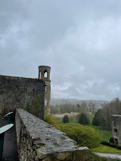 an old stone wall with a tower in the background on a gloomy day,