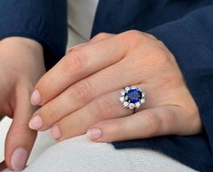 a woman's hand with a ring on it and a blue stone in the middle