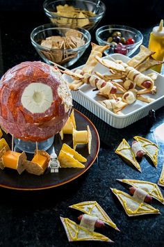 an assortment of cheeses, crackers and hot dogs on a table with other snacks