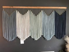 three different shades of blue, grey and white hanging on a wall next to a potted plant