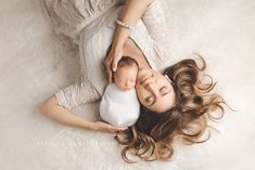 a woman holding a baby in her arms while laying on the floor with it's eyes closed