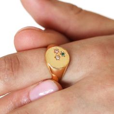 Featuring a trendy hammered face on a polished gold band, the textured surface of the ring holds three tiny flower cutouts. Each cutout is infilled with a cubic zirconia crystal in shades of green, pink and clear. Ideal for stacking with other pieces, this bold ring is made to stand out. Layer with thinner rings for a dressed-down look or dress up with other chunky accessories. Available in two sizes Made from 14ct gold plated brass, cubic zirconia crystal Gold Signet Ring With May Birthstone, Gold Cubic Zirconia Emerald Birthstone Ring, Gold Emerald Ring With Cubic Zirconia Birthstone, Gold Flower Ring With Emerald, Gold Flower Ring With May Birthstone, Happy Anniversary Gifts, Chunky Accessories, Angel Jewelry, Bold Rings