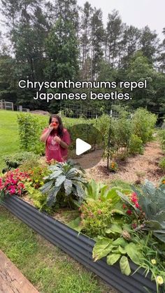 a woman standing in front of a garden filled with plants