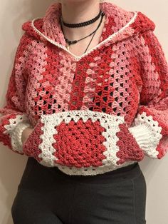 a woman wearing a red and white crocheted sweater with hearts on the chest