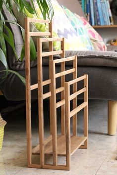 a wooden shelf sitting on top of a floor next to a couch and potted plant